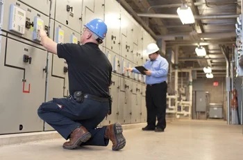 Workers inspecting a wall of equipment.